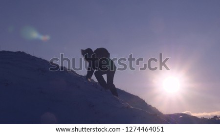 Climber climbs snowy mountain in rays of bright sun. tourist makes climb to top on background of beautiful sky. man moves to top to his success.
