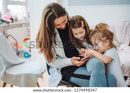 Mom and two daughters are looking for something in the smartphone