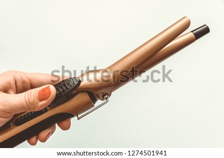 hand holding hair curling iron with ceramic plates on white background