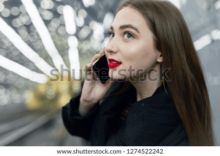 Pretty girl walk into the metro station while look at her phone. - Image