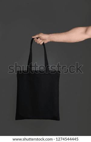 Man holding cotton shopping eco bag on grey background. Mockup for design