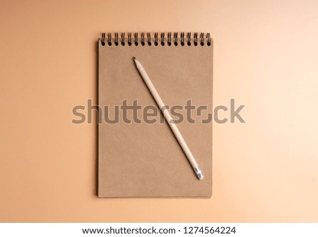 The notebook, pencil on color orange background. Flat lay top view.