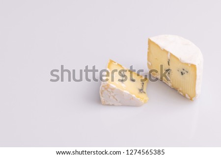 Blue cheese with white surface, isolated on white background, soft light, studio photo, angle view. Mix of gorgonzola and camembert / brie cheese.