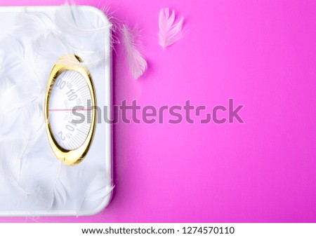 weighing scale feather on pink background, top view