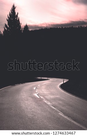Curved road at sunrise and forest silhouette. Empty street in the Black Forest National Park, Germany