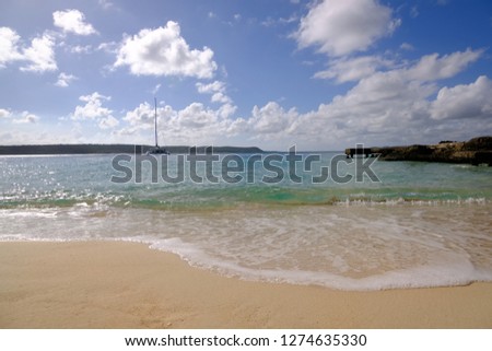 Sunny day in Cuba bay. Beach with ocean and catamaran on the background  