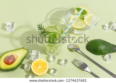 A glass beaker, of cucumber water, fruits and cutlery on a light green background. Minimalistic creative concept. Copy space.