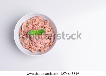 Canned tuna in a white bowl, isolated on white background; top view, copy space, soft light, studio shot