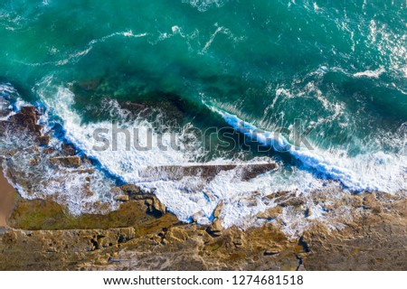Top down view of the waves crashing onto the rock shelf at Dudley Beach - Newastle Australia. Aerial view of rugged coastal lanscape.