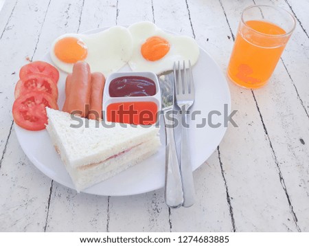 Breakfast, fried egg, sausage, sandwich and orange juice served on the morning of the day.