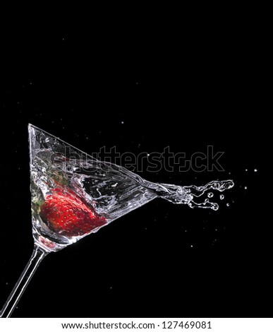 Martini drink splashing out of glass, isolated on black background