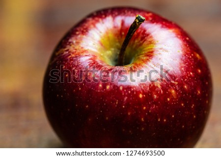 Close up picture of an juicy red apple in dark background, dramatic light, wooden vintage board.