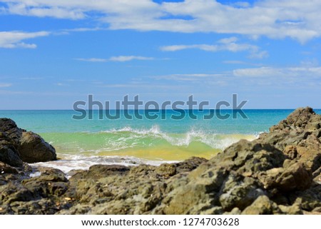 Seashores of New Zealand; beautiful seascape and bright blue ocean. Rocky foreground with clear and colourful waves.