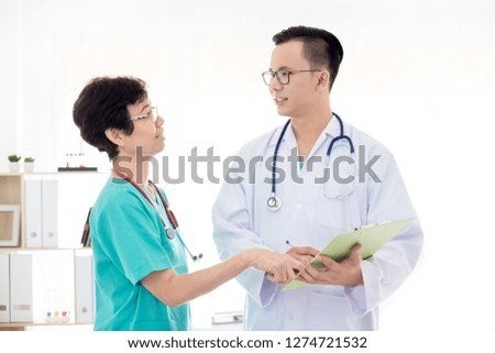 Asian doctor talking with health worker about patient treatment order, doctor holding patient chart
