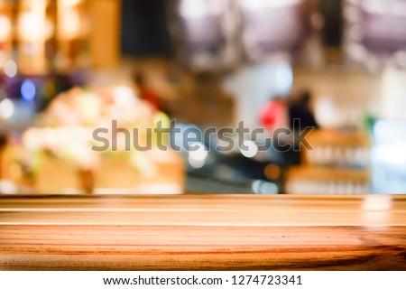 Empty wooden table for present product on coffee shop or soft drink bar blur background with bokeh image.
