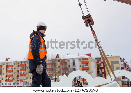 Portrait of an assembler worker in a jacket with a hood and a white helmet at unloading ice plates