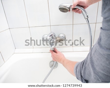 Plumber uninstalling shower hose from a bathtub faucet