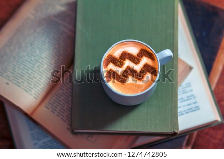 a cup of cappuccino with a zodiac sign of Aries on milk foam
