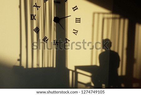 Sun shining shadows on the wall with clock.