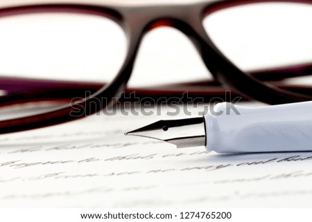 white fountain pen on letter, glasses behind