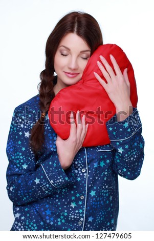 Picture of happy and smiling woman with heart-shaped pillow on white background on Valentines Day