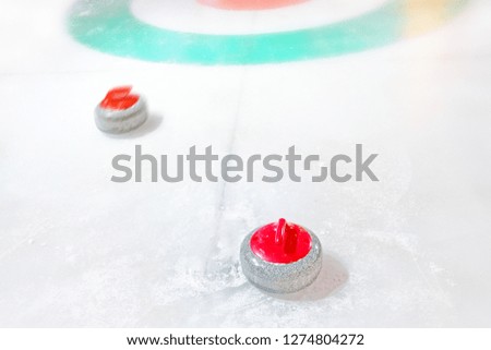 white winter sport curling game outdoor activity granite red stones on natural ice with snow landscape background closeup view holiday winter fun recreation scene
