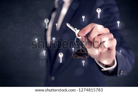 Businessman in suit holding keys with keys graphics around and dark background