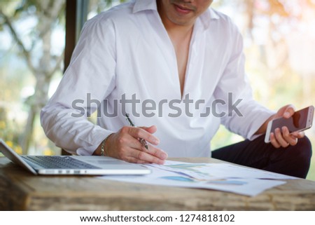  Business man busy working the charts and graphs showing and using laptop   in office background