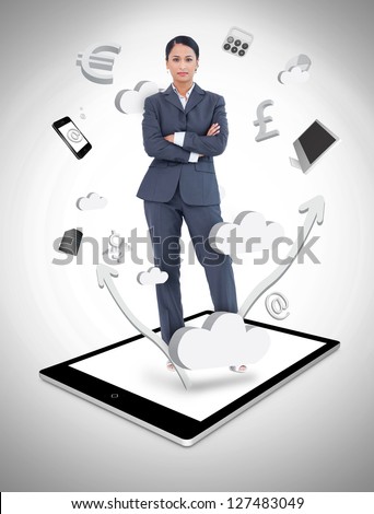 Serious businesswoman with crossed arms on a tablet pc against a digital gray background