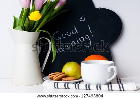 bouquet of tulips in a white jug, morning coffee, fruit and chalk board with the inscription on a white background