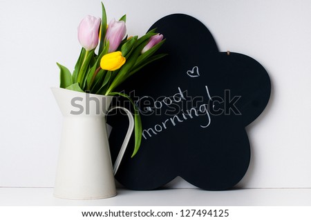 bouquet of tulips in a white jug and chalk board with the inscription on a white background