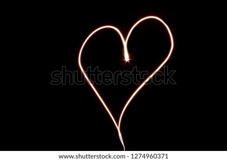 slow shutter speed photo in the shape of a heart with a black background.                    