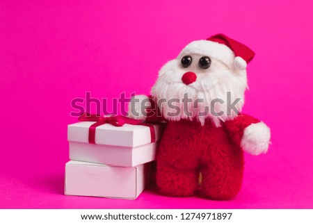 Toy cartoon santa with white gift boxes on a pink background.