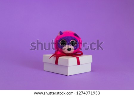 Toy cartoon mouse sits on a white gift box.