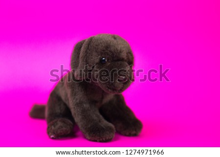 Toy cartoon puppy sits on a pink background.