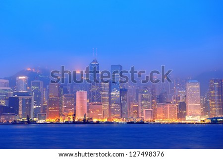 Hong Kong Victoria Harbor morning with urban skyscrapers over sea with blue tone and street light.