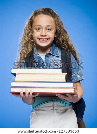 Smiling girl with backpack holding hardcover books