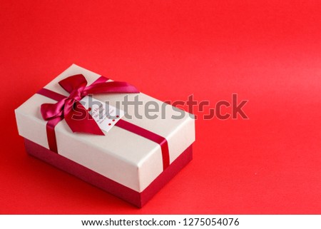 Gift box with a ribbon on a red background. The concept is suitable for love stories, birthdays and Valentine's Day