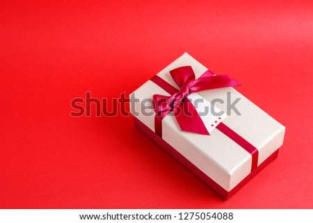 Gift box with a ribbon on a red background. The concept is suitable for love stories, birthdays and Valentine's Day