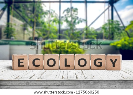 Ecology sign on a wooden table in a greenery with fresh green plants