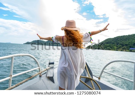 Red hair girl stayiing on a cruise boat in a white dress and hat,travel in Phu Quoc island near cable cars