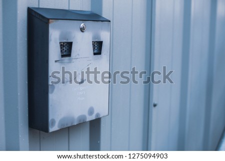 Closeup image of an exterior wall mounted smokers butt ashtray for smutting out cigarettes before entrance to the building
