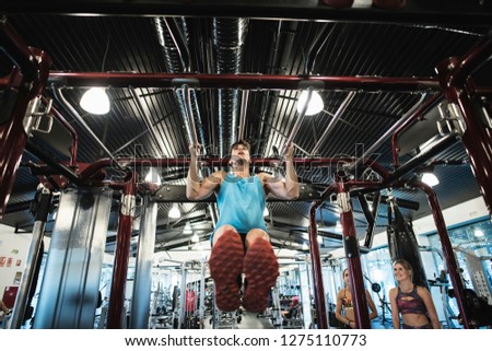 Young man training chin exercises in gym machine.