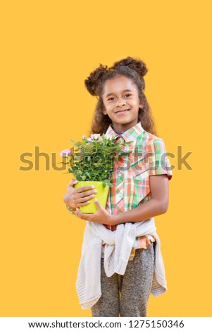Beautiful plant. Cheerful delighted girl smiling to you while holding her favourite flower Royalty-Free Stock Photo #1275150346
