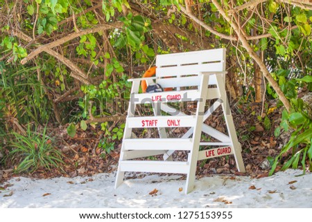 White life guard chair on the beach under the trees.