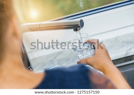 Beautiful woman filling glass with water in kitchen