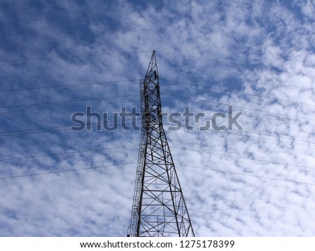 Electric Tower and Blue Sky - Photograph of a tall electric tower against a bright blue sky and white clouds. 