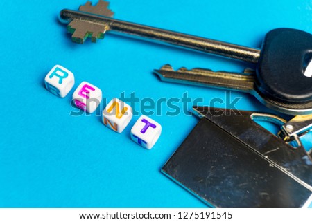 Inscription rent written colored cubes. Photo on the background of a key FOB in the shape of a house.