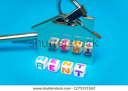Inscription rent written colored cubes. Photo on the background of a key FOB in the shape of a house.
