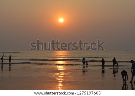 People washing their feet and watching mesmerizing sunset on a beach.